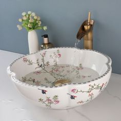 a bathroom sink with flowers on it and soap dispenser