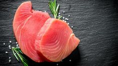 raw fish fillets with rosemary sprigs on black slate