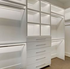 an empty walk in closet with white shelves and drawers