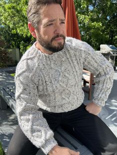 a man sitting on a bench wearing a sweater