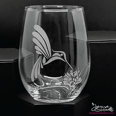 a wine glass with a hummingbird etched on the side, sitting on a table