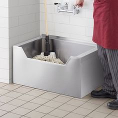 a person standing in front of a sink with mop and bucket on the floor