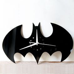 a clock with a batman symbol on it is hanging from the side of a wall