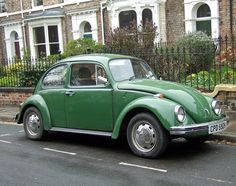 an old green car parked on the side of the road