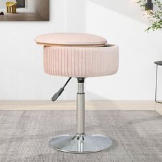 a pink velvet stool with chrome base and foot rest in front of a white wall