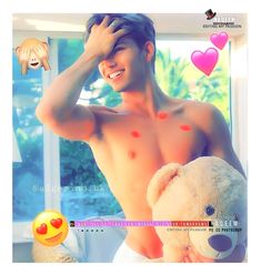 a shirtless man holding a teddy bear in front of a window with hearts on it