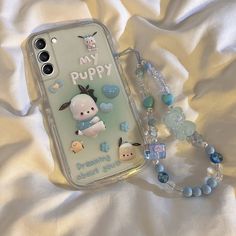 a cell phone case with an adorable puppy on it next to a beaded necklace