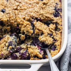 blueberry cobbler in a white casserole dish with a spoon on the side