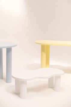 three different colored tables sitting next to each other on a white surface with light coming from behind them