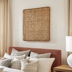 a bed with pillows and blankets on top of it next to a lamp in front of a window