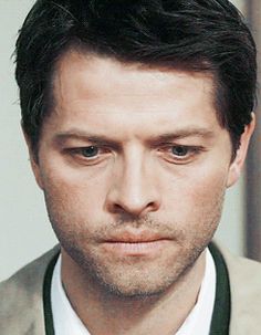 a close up of a person wearing a suit and tie with a serious look on his face