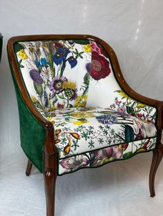 a green velvet chair with flowers and birds on the back, sitting in front of a white backdrop