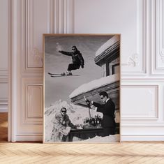 a black and white photo of two men on skis in the air above snow