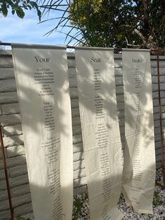 three white towels hanging from a clothes line in front of a brick wall and tree