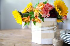 a vase filled with flowers sitting on top of a wooden table next to plates and utensils