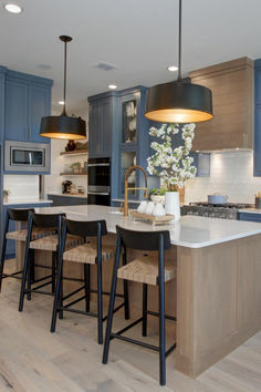 Blue cabinetry in the kitchen? The Eastland II's kitchen design shows this application off. Paired with a wooden, shiplap rangehood, this blue cabinetry proves to be versatile and stylish. Blue And Wooden Kitchen, White Oak And Blue Kitchen, Blue And Wood Kitchen Cabinets, Blue Kitchen Cabinets Farmhouse, Navy And Wood Kitchen, Natural Wood Kitchen Island, Kitchen Blue Island, Kitchen With Blue Island, Custom Home Floor Plans