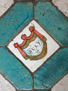 a close up of a tile with a coat of arms emblem on it's side