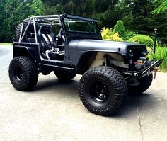 the jeep is parked on the side of the road in front of some trees and bushes