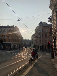 two bicyclists are riding down the street at sunset