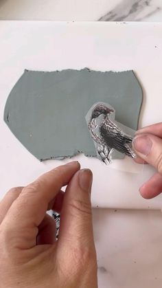 a person is peeling a piece of paper with a bird on it