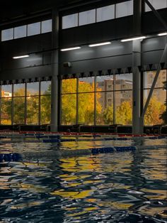 an indoor swimming pool with large windows and trees in the backgroung area