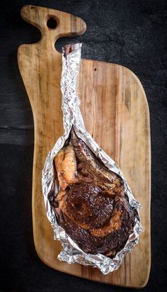 steak wrapped in foil on a cutting board