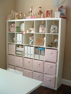 a white bookcase filled with lots of pink drawers