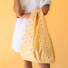 Say hello to your new must-have accessory for spring and summer - the Dreamy Daisy Reusable Bag! With its vibrant yellow, orange and ivory floral print, this nylon bag is not only perfect for grocery trips and beach days, but makes an adorable everyday accessory. Ditch single use plastic and strut your stuff in style with this versatile eye-catching Dreamy Daisy Reusable Bag. Summer Floral Print Bags For Everyday Use, Yellow Floral Print Travel Bag, Floral Print Bags For Everyday Summer Use, Reusable Bags For Spring, Yellow Floral Print Bag For Daily Use, Yellow Floral Print Bags For Daily Use, Yellow Floral Print Everyday Bag, Everyday Yellow Floral Print Bags, Summer Shopping Bags With Floral Print