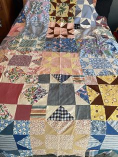 a bed covered in lots of different colored quilts