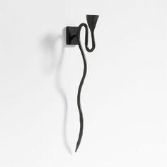 a black hook is attached to the wall with a long curved handle on it's side