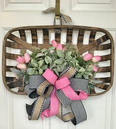 a wreath with pink roses and greenery hangs on the front door