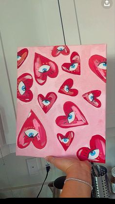 a person holding up a painting with hearts on it