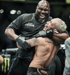 two men embracing each other in the middle of a boxing ring with one man wearing black gloves