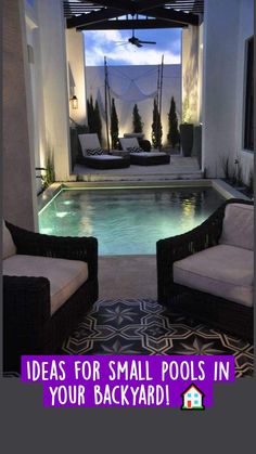 two wicker chairs sitting in front of a swimming pool at night with lights on