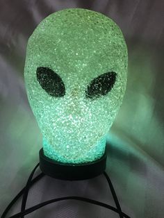 an alien head lamp is lit up with green and black glitters on it's face