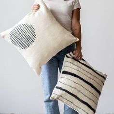 a woman holding two pillows in her hands