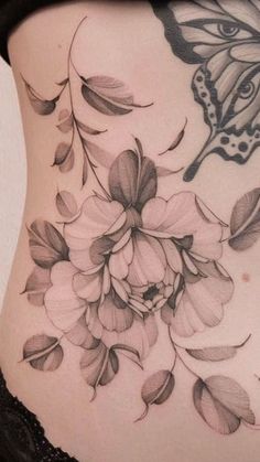 a woman's stomach with flowers and butterfly tattoo on her side ribcage