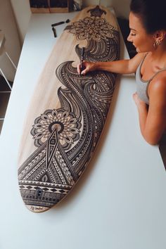 a woman standing next to a wooden surfboard on top of a white countertop