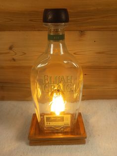 an empty glass bottle sitting on top of a wooden stand with a lit candle in it