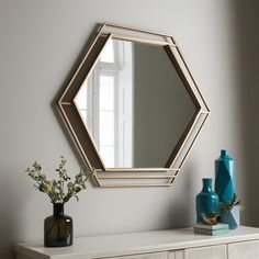 a mirror sitting on top of a dresser next to a vase