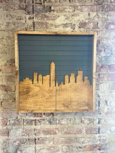 a wooden frame with a cityscape on it in front of a brick wall