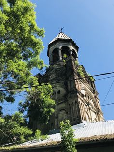 an old church steeple with a cross on it's roof and trees in the foreground