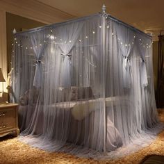 a canopy bed with mosquito netting and fairy lights on the top, in a bedroom