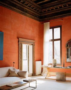 a living room with red walls and white furniture