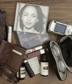 an assortment of personal items laid out on top of a wooden table next to a cell phone