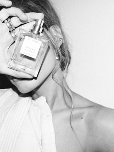 a woman holding a bottle of perfume in front of her face