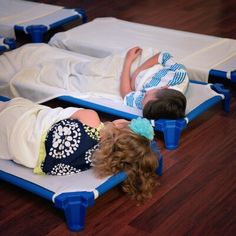 two children laying on cots in a room