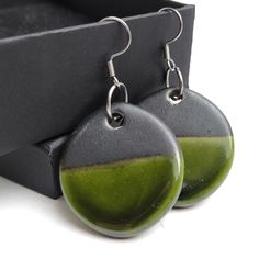 two green and black earrings sitting on top of a box