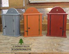 three different colored wooden cupboards sitting next to each other on top of a table