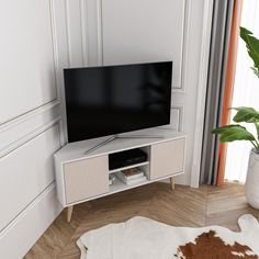 a flat screen tv sitting on top of a white entertainment center next to a potted plant